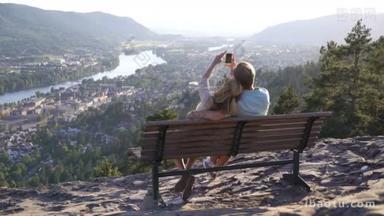 浪漫情侣坐在木凳上欣赏着山谷中的小镇和河流
